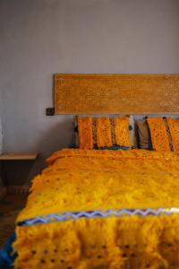 a bed with a yellow blanket and pillows on it at Berber Beldi Camp in Imsouane +68 photos