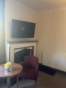 a living room with a chair and a tv over a fireplace at Rowardennan Hotel in Rowardennan