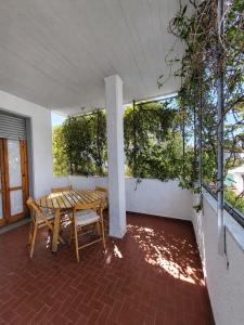 a table and bench on a patio with trees at Kronos House in Torre del Lago Puccini