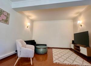 a living room with a chair and a tv at O Jardim Mágico in Teixoso