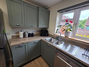 a kitchen with green cabinets and a sink and a window at 3 bed house in Winterbourne Abbas in Winterborne Abbas