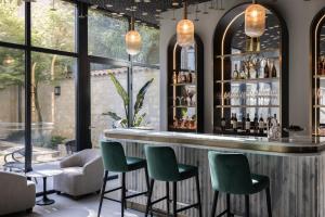 a bar with green chairs in a room with windows at Hotel des Quinconces Bordeaux Centre in Bordeaux