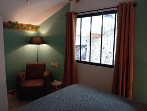 a bedroom with a bed and a chair and a window at La Pépite du Sauternais in Preignac