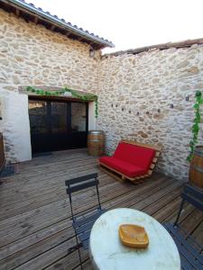 a patio with a red couch and a table and chairs at La Pépite du Sauternais in Preignac +2 photos