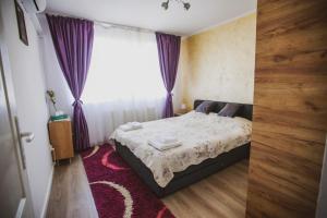 ein Schlafzimmer mit einem Bett und einem Fenster mit lila Vorhängen in der Unterkunft Sun View Boulevard in Alba Iulia