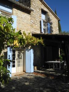 una casa de piedra con una puerta blanca y una mesa en Le Rourebeau, en Mollans-sur-Ouvèze