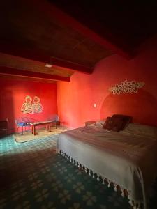 a bedroom with red walls and a bed and a table at Ojo de Luna Teotitlan in Teotitlán del Valle +12 photos