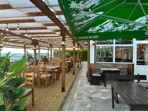 a restaurant with wooden tables and chairs and a green umbrella at Apartments Panorama Ravda in Ravda