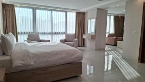 ein Schlafzimmer mit einem großen Bett, Stühlen und Fenstern in der Unterkunft فندق جواهر العبدلي - Jawaher Hotel in Amman