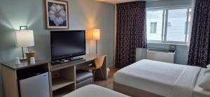 a hotel room with a bed and a desk with a television at Mammas Inn in Niagara Falls