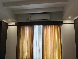 a room with a window with a curtain and a air conditioner at Continento the classic hotel in Malappuram +2 photos
