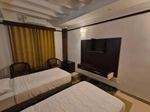 a hotel room with two beds and a flat screen tv at Continento the classic hotel in Malappuram