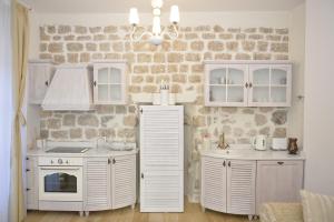 eine Küche mit weißen Schränken und einer Steinmauer in der Unterkunft Palazzo Max and Alex Apartments in Kotor