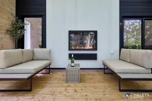 a living room with two couches and a table at Chalet Altitude Riverfront Pet-Friendly in Saint-Raymond