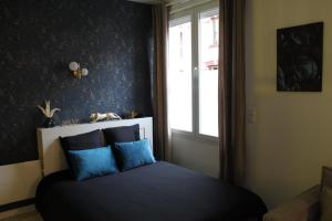 a bedroom with a bed with blue pillows and a window at Spa des Sacres - Suite avec Jacuzzi Privatif in Reims