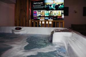 a hot tub in a room with a tv at Spa des Sacres - Suite avec Jacuzzi Privatif in Reims
