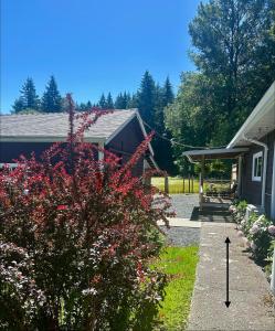 a yard with a house and a bush with flowers at Maple Woods B&B in Honeymoon Bay