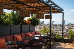 a patio with tables and chairs and a view of a city at Kimpton Vividora Hotel by IHG in Barcelona