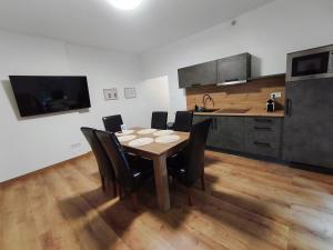 a kitchen with a wooden table and black chairs at Central Apartman Tatabánya in Tatabánya