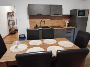 a kitchen with a wooden table with chairs around it at Central Apartman Tatabánya in Tatabánya +8 photos