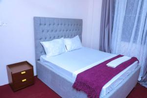 a bedroom with a white bed with a purple blanket at Zanzibar Rahaa in Dar es Salaam