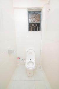 a white bathroom with a toilet and a window at Zanzibar Rahaa in Dar es Salaam +4 photos