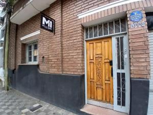 a brown brick building with a wooden door at MillaUno Hostel in Córdoba