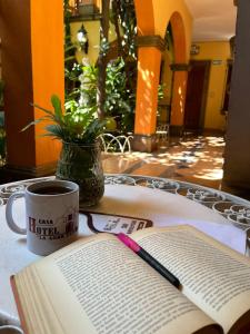 a book on a table with a cup of coffee and a pen at Hotel Casa La Gran Señora in Tequila