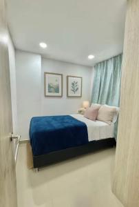 a bedroom with a bed with blue sheets and a window at Apartamento Tranquilo y Acogedor in Sabaneta