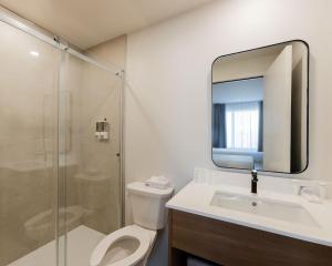 a bathroom with a toilet and a sink and a mirror at Hôtel l'Empress in Rimouski
