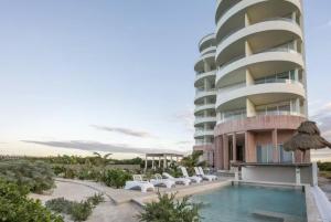 a building with a swimming pool next to a resort at Oceanfront Condo with Pool and Views Telchac | Depto B52 in Xtampú