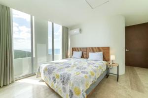 a bedroom with a large bed and large windows at Oceanfront Condo with Pool and Views Telchac | Depto B52 in Xtampú +20 photos