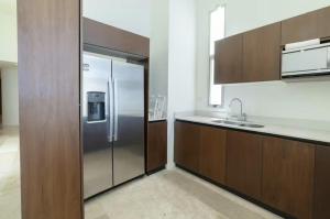 a kitchen with a stainless steel refrigerator and wooden cabinets at Oceanfront Condo with Pool and Views Telchac | Depto B52 in Xtampú