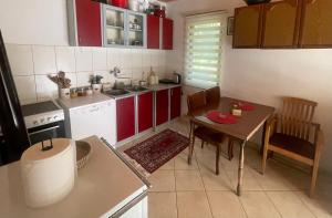 a kitchen with red cabinets and a table and a table and chairs at Tresnjin hlad in Limljani