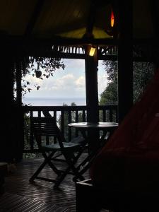 a table and chair on a porch with a view of the ocean at Hutte Karaib Reve de Robinson Une cabane perchee au cœur de la nature tropicale vue mer in Terre-de-Bas