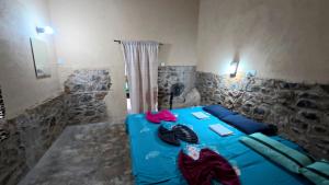 a blue bed in a room with a stone wall at Achinthya Nature Resort in Avissawella +51 photos
