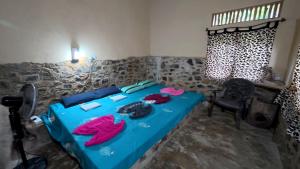 a bedroom with a blue bed with clothes on it at Achinthya Nature Resort in Avissawella