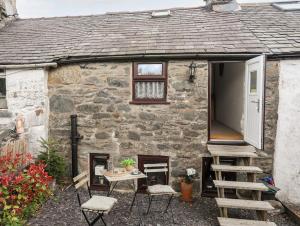 a stone cottage with a table and chairs in front of it at Merrion Cottage Penmachno Betws y Coed Conwy in Penmachno