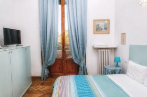 a bedroom with a bed and a window with blue curtains at Villa Gini in Pisa