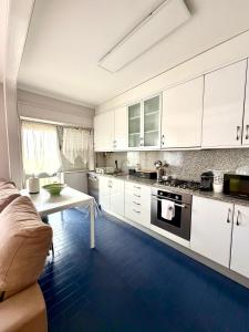 a kitchen with white cabinets and a table and a couch at DaKing in Vila do Conde