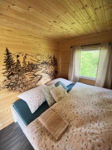a bedroom with a bed in a wooden wall at Útulná maringotka uprostřed přírody pro dokonalý odpočinek ve dvou in Borovy