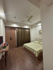 a bedroom with a bed and a table and a tv at the Aurelia estate studio apartment Alpha 2 in Greater Noida