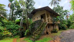 a small house with a staircase in the woods at Achinthya Nature Resort in Avissawella