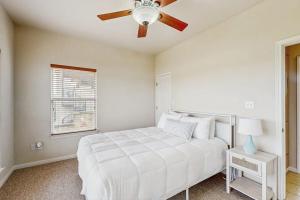 a bedroom with a white bed and a ceiling fan at Scenic Riverfront Home with Boat Access, Private Pool/Hot Tub - Close to Shopping in Lago Vista
