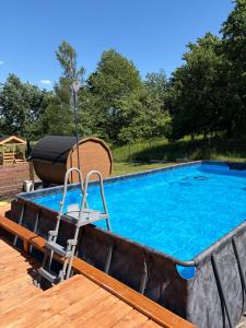a swimming pool with a chair next to a wooden deck at LoftLove roztocze domek in Jędrzejówka