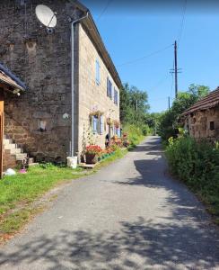 an empty road next to a stone building at La Petite Ferme d'Autrefois in Saint-Georges-Nigremont