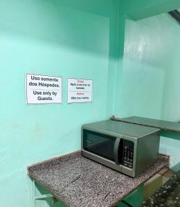 a microwave on a counter with a sign on the wall at Quarto no centro 207 in Manaus