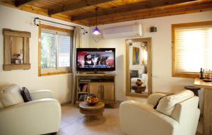 a living room with two white couches and a television at בקתות באהבה בוטיק in Rosh Pinna