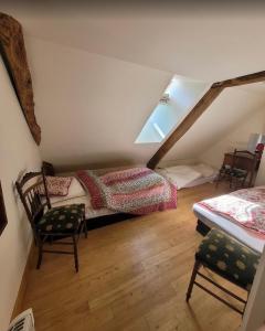 a attic room with two beds and a chair at La Petite Ferme d'Autrefois in Saint-Georges-Nigremont