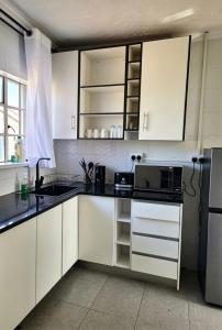 a kitchen with white cabinets and a microwave at 2 Bed Cottage close to Westgate Shopping Centre in Harare